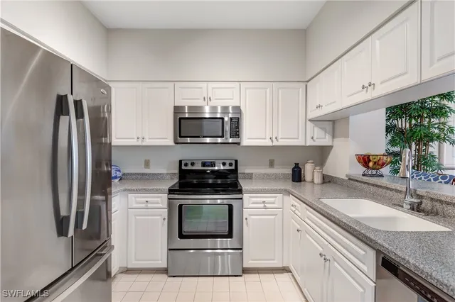 a kitchen with white cabinets stainless steel appliances and a sink