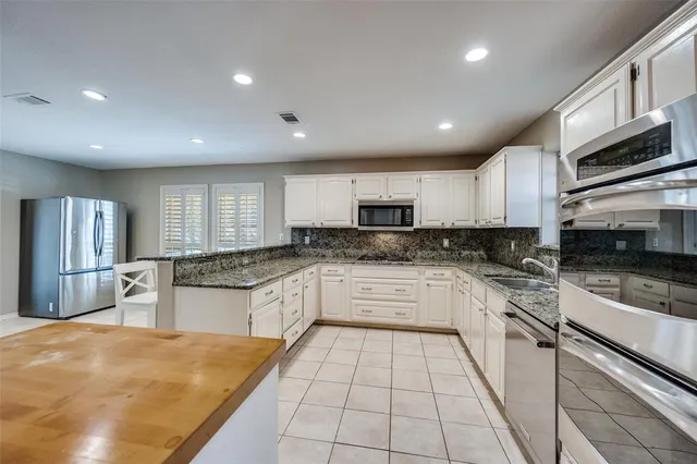 a large kitchen with stainless steel appliances granite countertop a stove a sink a microwave and a refrigerator