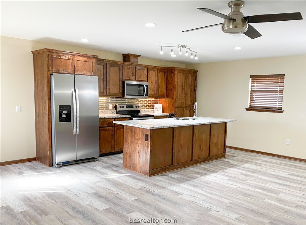 a kitchen with stainless steel appliances granite countertop a refrigerator a sink a stove a microwave a counter top space and cabinets