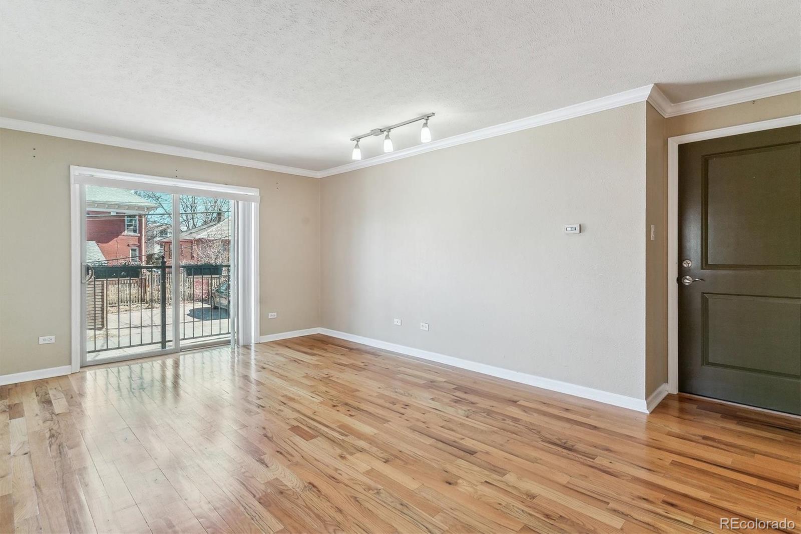 1330 Elizabeth Street, Unit 8 Denver, CO 80206 - Photo 3 of 15 a view of an empty room with wooden floor and a window