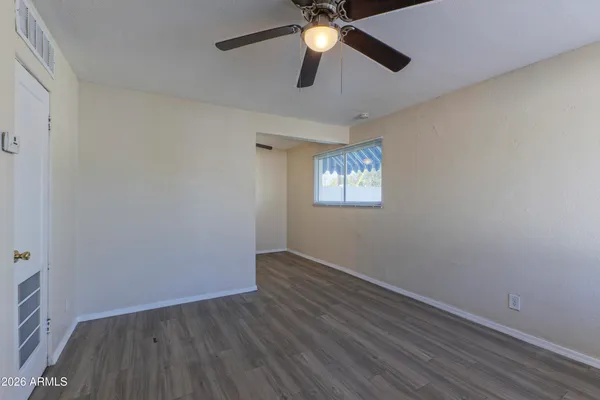 an empty room with wooden floor ceiling fan and windows