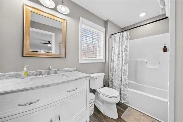a bathroom with a granite countertop sink toilet and shower