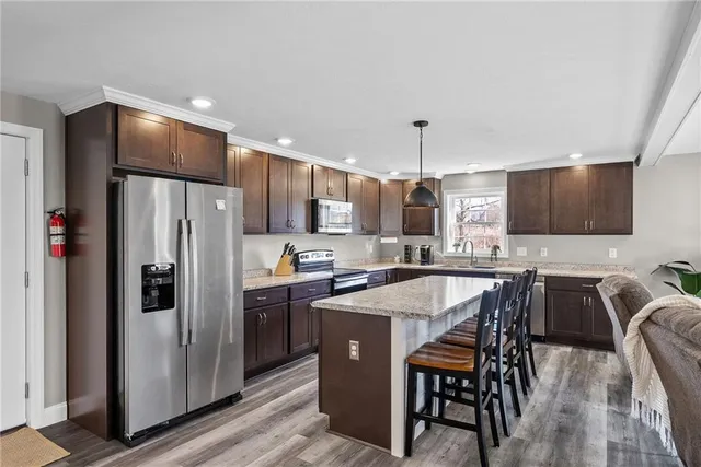 a kitchen with stainless steel appliances a table chairs refrigerator and microwave