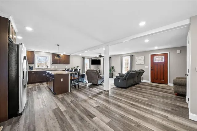 a kitchen with stainless steel appliances kitchen island granite countertop a refrigerator oven stove a dining table and chairs with wooden floor