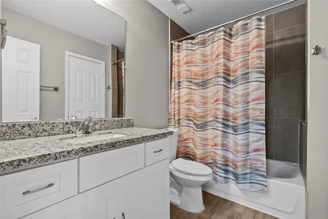 a bathroom with a granite countertop sink a toilet and shower curtain