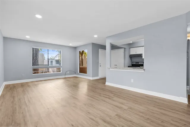 a view of an empty room with a window and wooden floor