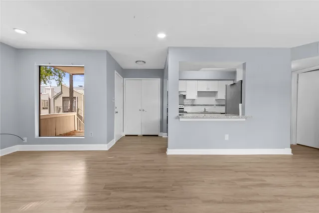 a view of kitchen and empty room with wooden floor