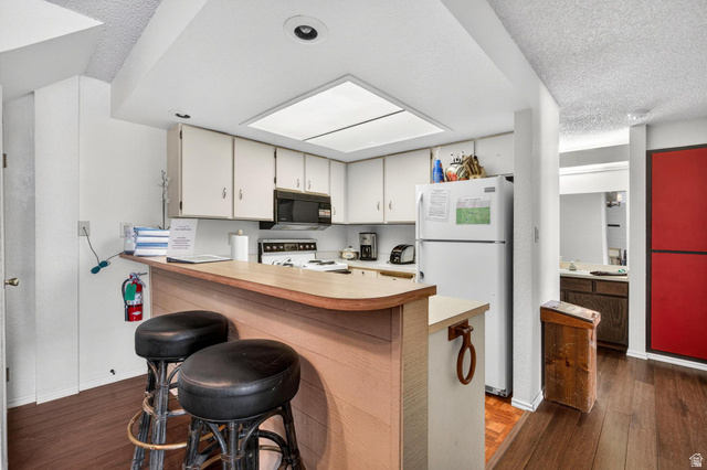 407 South Vasels Road, Unit 24 Brian Head, UT 84719 - Photo 9 of 63 Kitchen featuring light countertops, a breakfast bar area, white appliances, dark wood-style floors, and a textured ceiling