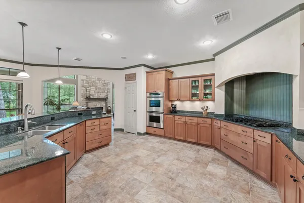 a large kitchen with kitchen island granite countertop a large counter top stainless steel appliances a sink and cabinets