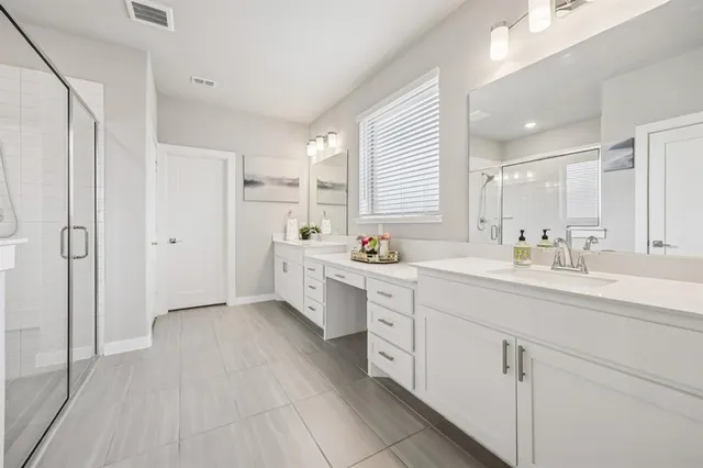 a large white bathroom with a double vanity sink a mirror and a bathtub
