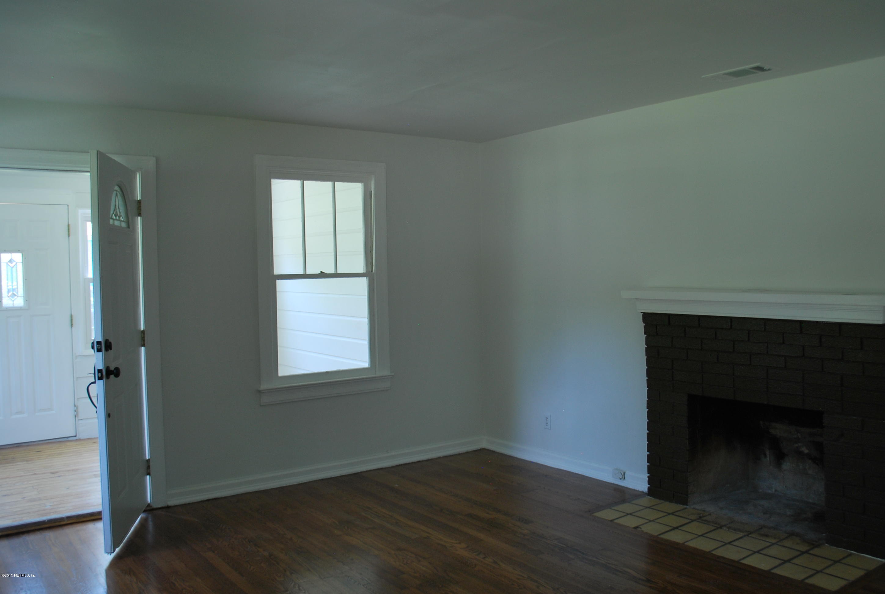 4603 Sunderland Road Jacksonville, FL 32210 - Photo 19 of 20 an empty room with wooden floor fireplace and windows