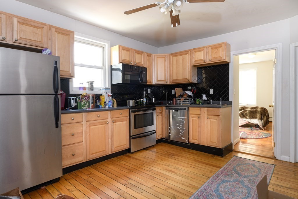 a kitchen with stainless steel appliances a refrigerator a sink a stove and white cabinets