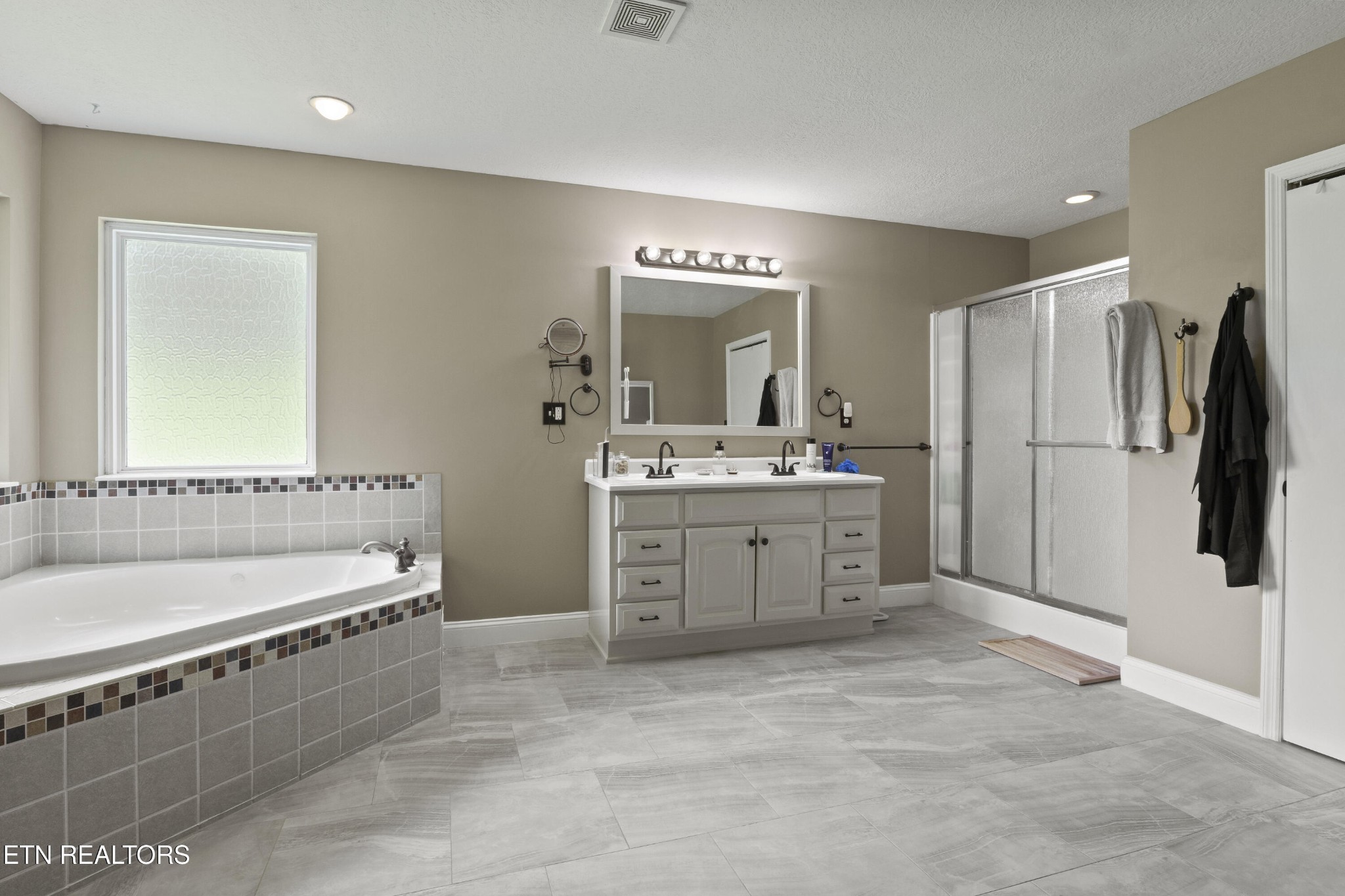 99 Reservoir Road Norris, TN 37828 - Photo 19 of 47 a spacious bathroom with a double vanity sink a mirror and a bathtub