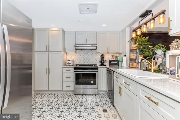 a kitchen with granite countertop a stove a sink and a refrigerator