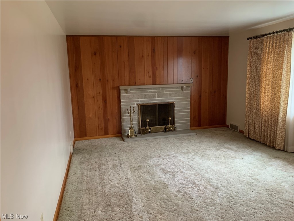 4530 8th Street Northwest Canton, OH 44708 - Photo 5 of 8 Unfurnished living room with a stone fireplace, wooden walls, and light colored carpet