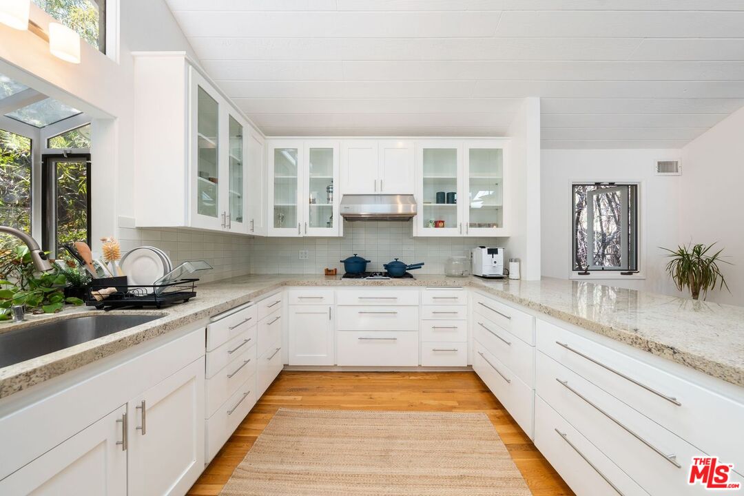 22760 Chamera Lane Topanga, CA 90290 - Photo 22 of 52 a large white kitchen with stainless steel appliances granite countertop a sink and cabinets