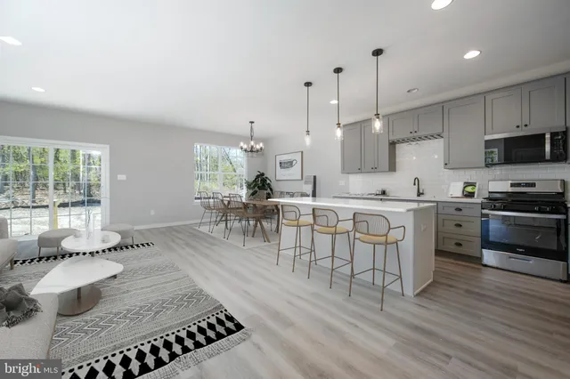 a open kitchen with stainless steel appliances granite countertop a stove top oven a sink dishwasher and a dining table with wooden floor