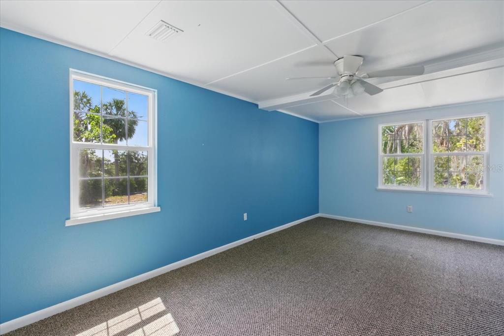12301 Cedar Street Cedar Key, FL 32625 - Photo 17 of 38 an empty room with windows and ceiling fan