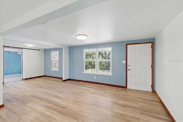 a view of an empty room with wooden floor and a window