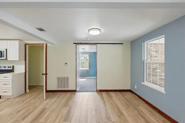 a view of an empty room with wooden floor and a window