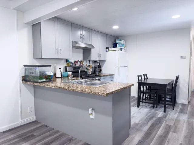 a kitchen with granite countertop a table chairs microwave and cabinets
