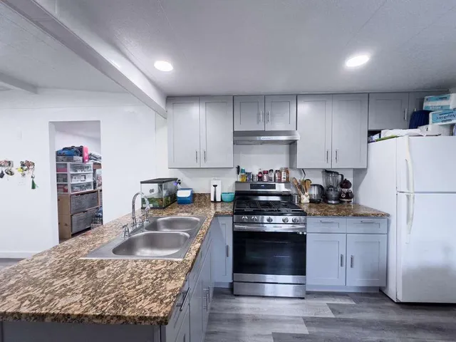 a kitchen with granite countertop a sink stove and refrigerator