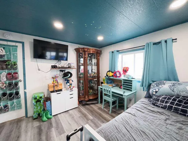 a living room with furniture a flat screen tv and a refrigerator