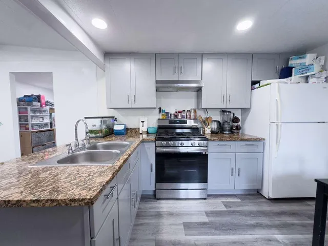 a kitchen with granite countertop a sink stove and refrigerator