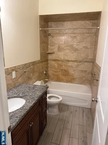 a bathroom with a granite countertop sink a toilet and bathtub