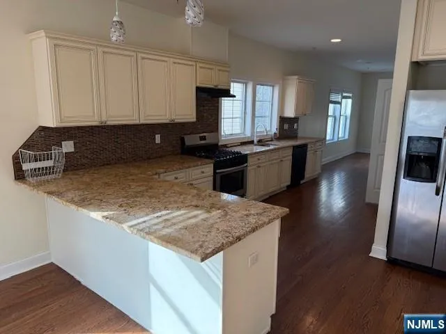 a kitchen with granite countertop a sink a counter top space appliances and cabinets