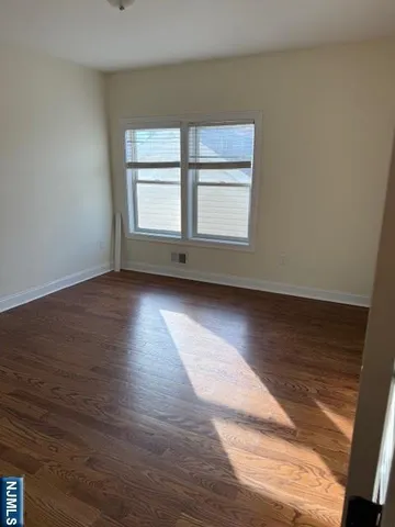 a view of an empty room with wooden floor and window