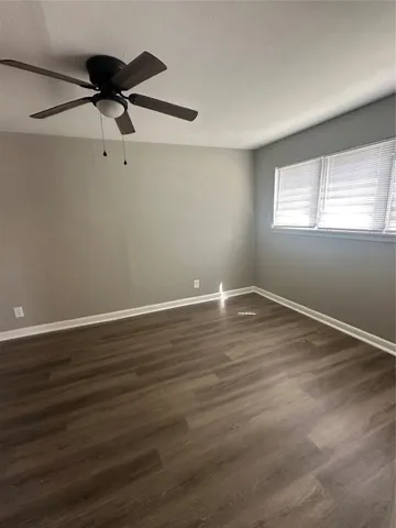 a view of room with hardwood floor a ceiling fan and window
