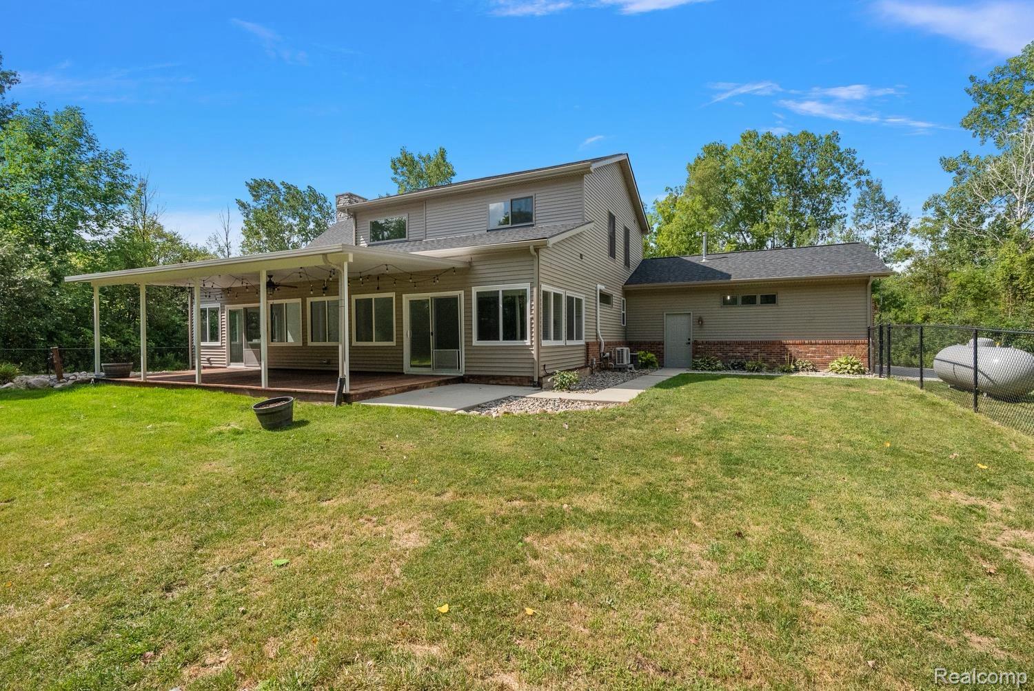 13392 Belsay Road Millington, MI 48746 - Photo 3 of 18 Expansive rear exterior with an extended covered patio featuring multiple access points