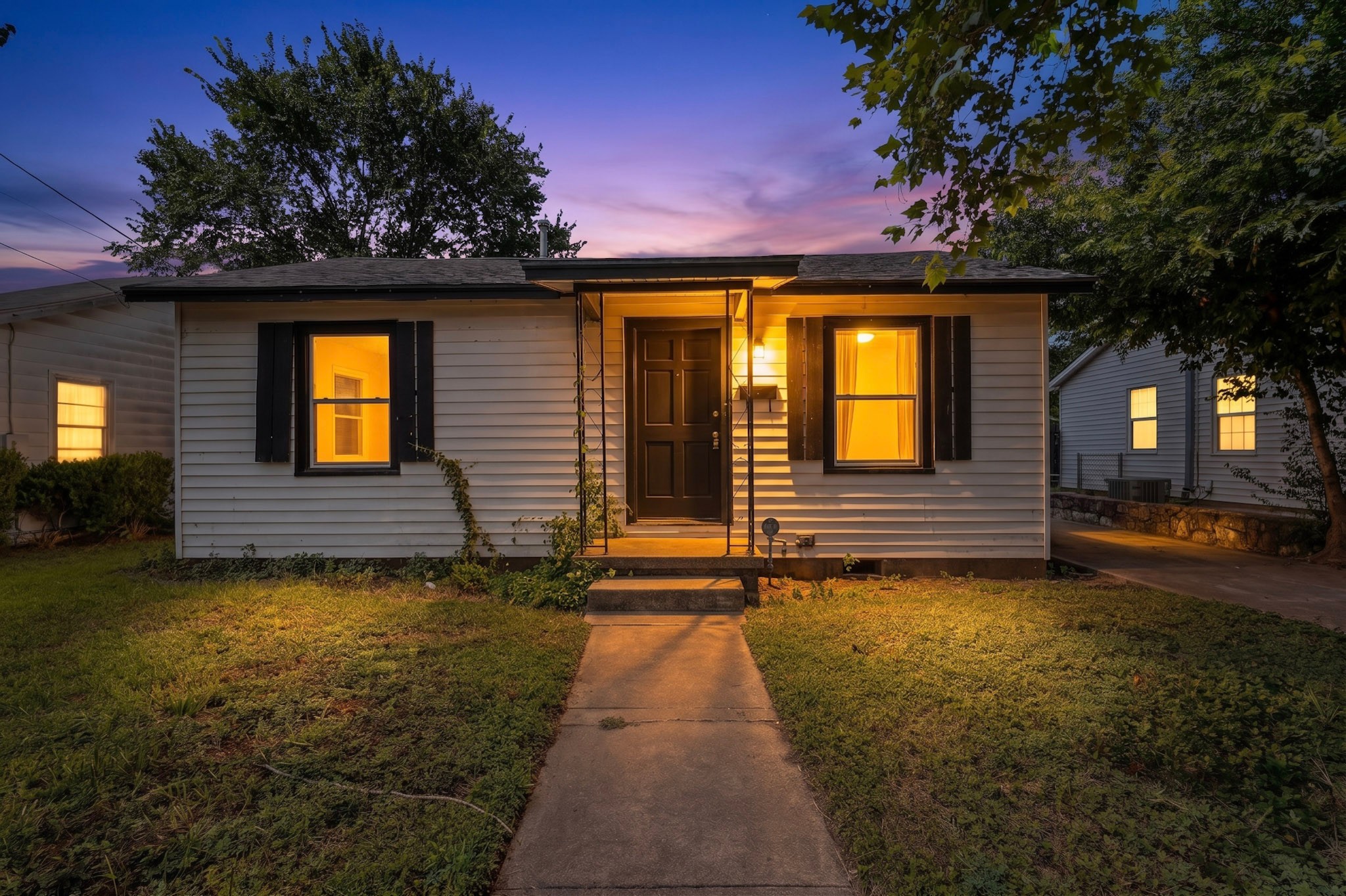 4703 Leslie Avenue Austin, TX 78721 - Photo 1 of 34 A welcoming front path leads to a home with classic white siding and contrasting dark shutters under a twilight sky.