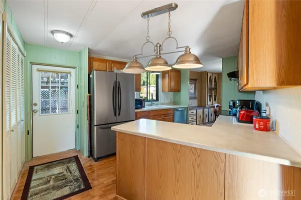 a kitchen with stainless steel appliances granite countertop a sink a refrigerator and a wooden cabinets
