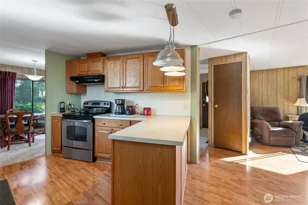 a kitchen with stainless steel appliances granite countertop a refrigerator a sink dishwasher a stove and white cabinets with wooden floor