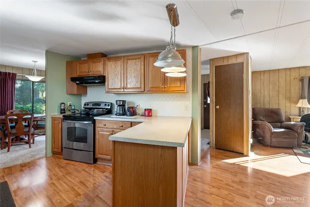 a kitchen with stainless steel appliances granite countertop a refrigerator a sink dishwasher a stove and white cabinets with wooden floor