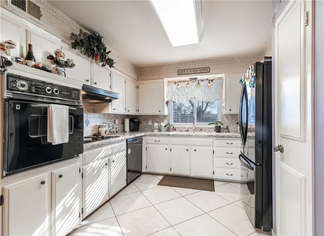 a kitchen with granite countertop white cabinets and black appliances