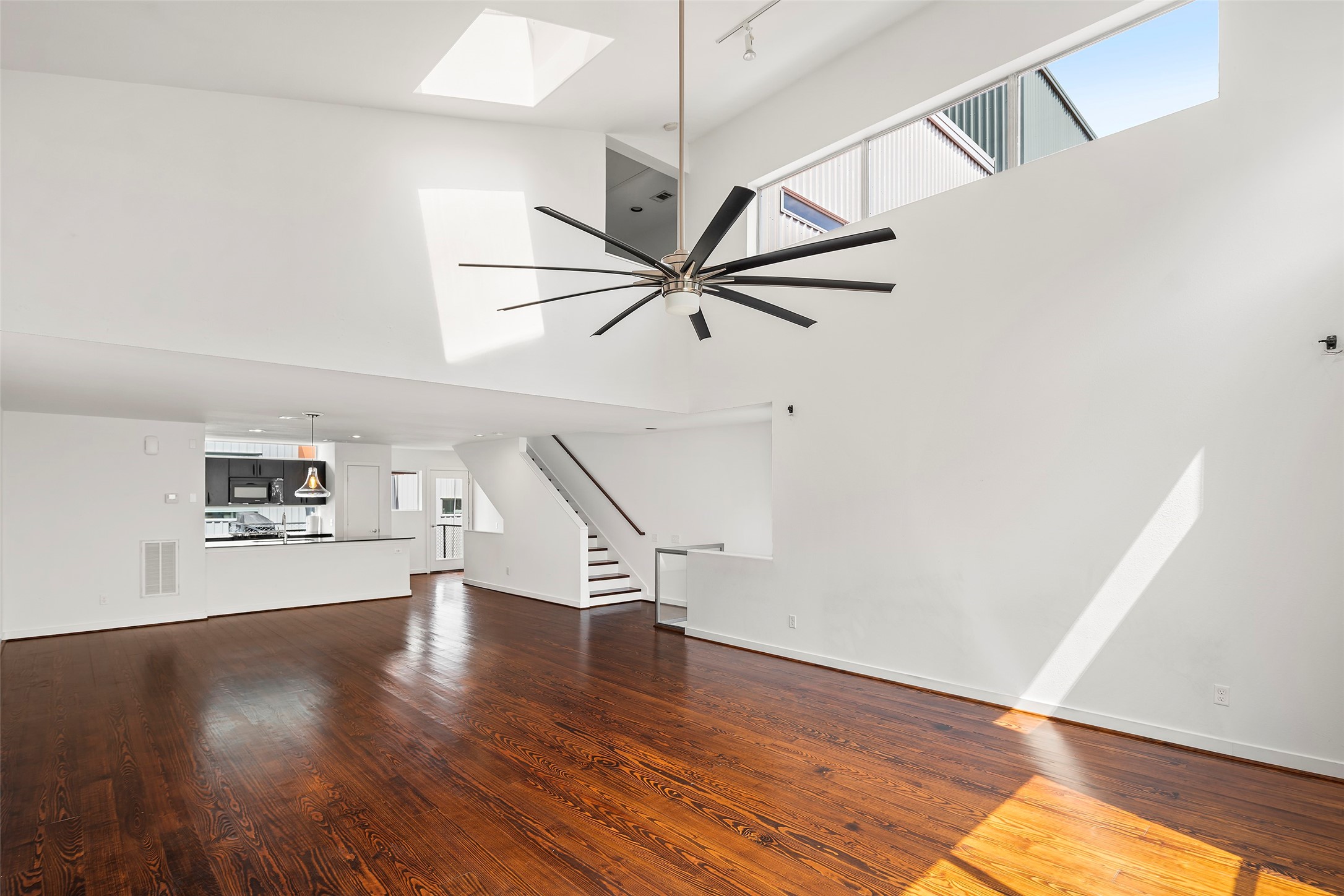 a view of a livingroom with wooden floor a ceiling fan and staircase