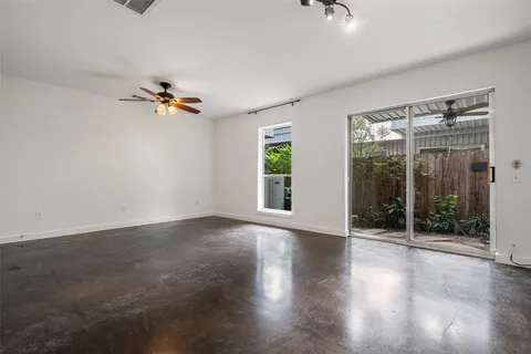 an empty room with wooden floor and a ceiling fan