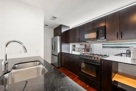 a kitchen with stainless steel appliances granite countertop a stove a sink and a microwave