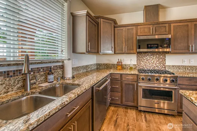 a kitchen with stainless steel appliances granite countertop a sink a stove and cabinets