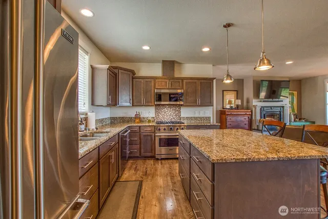 a kitchen with stainless steel appliances granite countertop sink stove refrigerator and cabinets