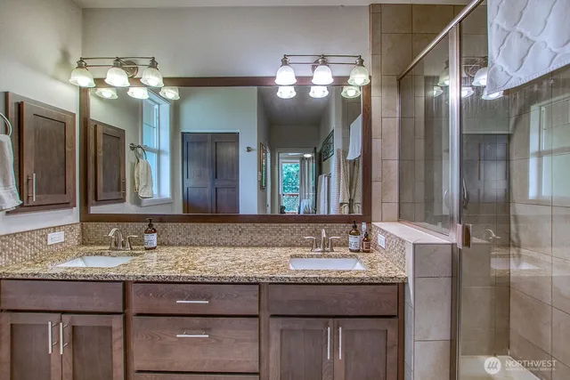 a bathroom with a granite countertop sink a large mirror and a shower