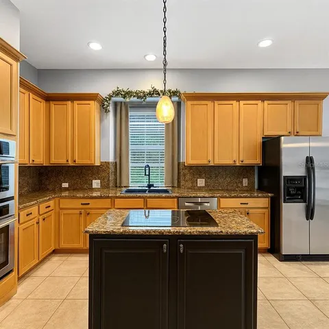 a kitchen with stainless steel appliances granite countertop a sink a stove and a refrigerator