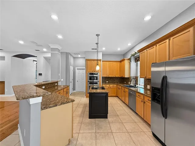 a kitchen with stainless steel appliances granite countertop a stove refrigerator and a sink