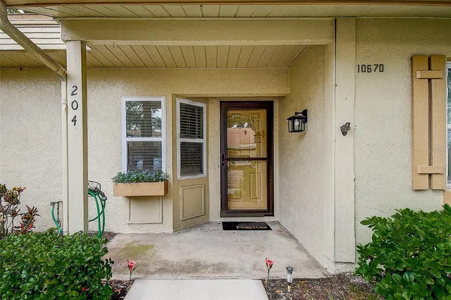 a view of a house with a chair and table and potted plants