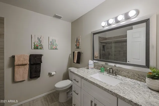 a bathroom with a granite countertop sink toilet and mirror