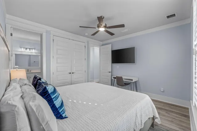 a bedroom with a bed a chair and a flat tv screen on the dresser