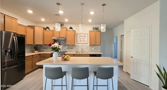 a kitchen with stainless steel appliances a dining table chairs refrigerator and microwave